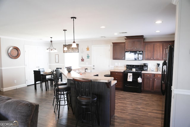 kitchen with a breakfast bar, black appliances, light countertops, and dark wood-type flooring