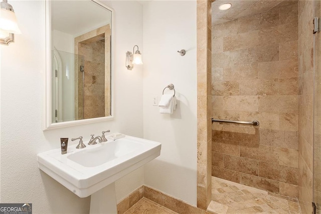 full bathroom featuring tiled shower and a sink