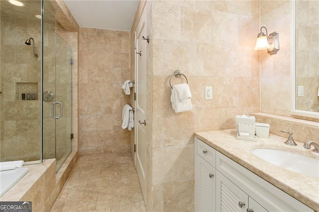 bathroom with vanity, tile walls, tiled tub, and a stall shower