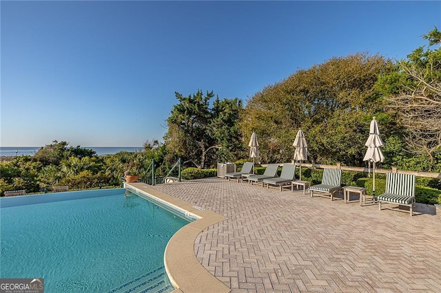 pool with a patio area and a water view