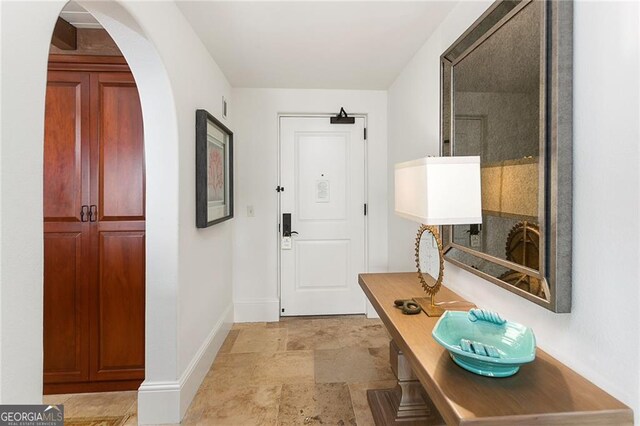 interior space with stone finish floor, baseboards, and arched walkways