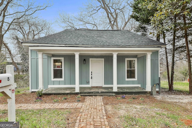 bungalow with a porch, board and batten siding, and a shingled roof