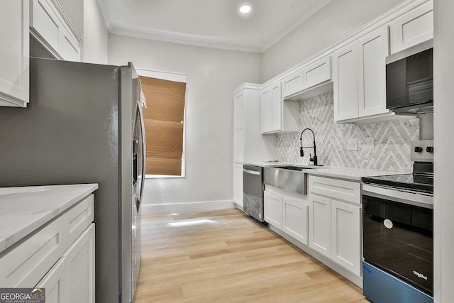 kitchen featuring tasteful backsplash, light wood-type flooring, ornamental molding, appliances with stainless steel finishes, and a sink