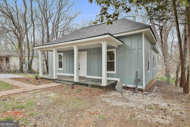 bungalow-style home featuring roof with shingles, board and batten siding, and covered porch