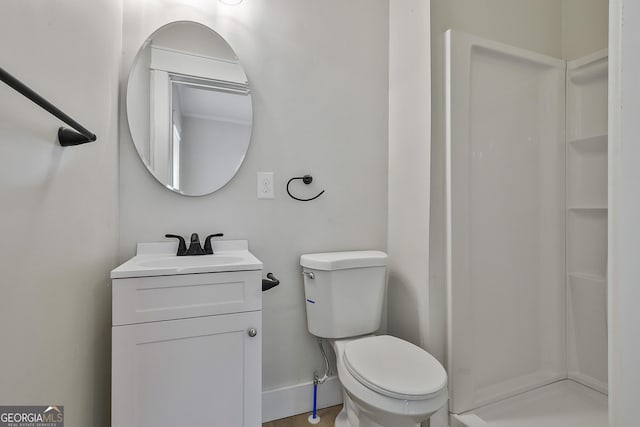 bathroom featuring baseboards, toilet, walk in shower, and vanity