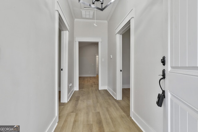 hallway with attic access, baseboards, light wood finished floors, and ornamental molding