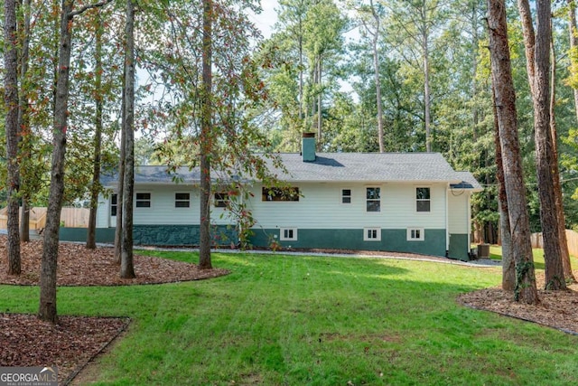 rear view of house with a lawn, fence, and a chimney