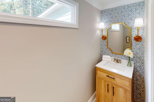 bathroom featuring vanity, crown molding, and wallpapered walls