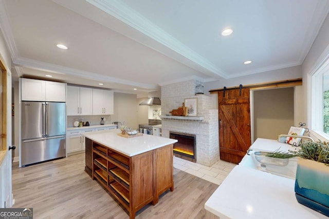 kitchen with crown molding, light countertops, appliances with stainless steel finishes, wall chimney exhaust hood, and a sink