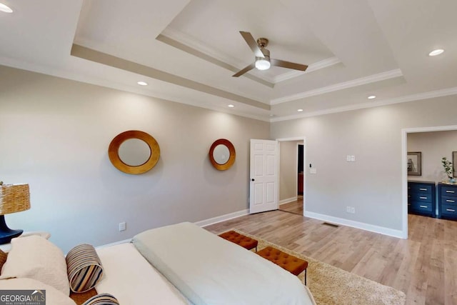 bedroom featuring a raised ceiling, crown molding, light wood-style floors, and baseboards