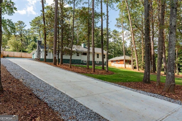 view of front of house with driveway, a front lawn, and fence