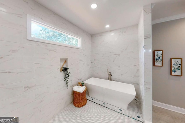 bathroom featuring recessed lighting, baseboards, a freestanding bath, and tile walls