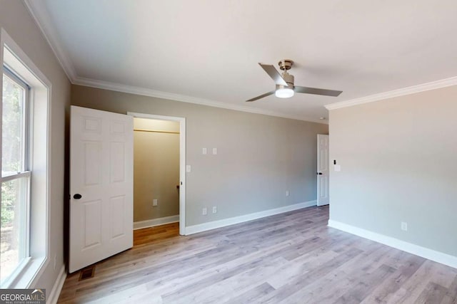 empty room with baseboards, ceiling fan, crown molding, and light wood finished floors