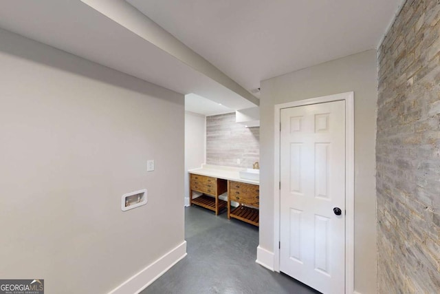 corridor featuring baseboards, finished concrete flooring, and an accent wall