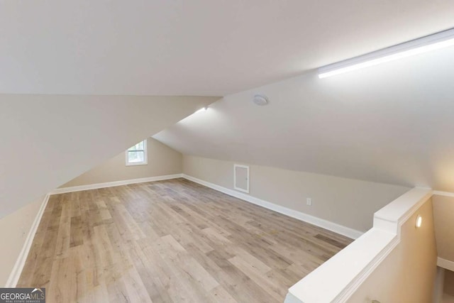 additional living space featuring baseboards, wood finished floors, and vaulted ceiling