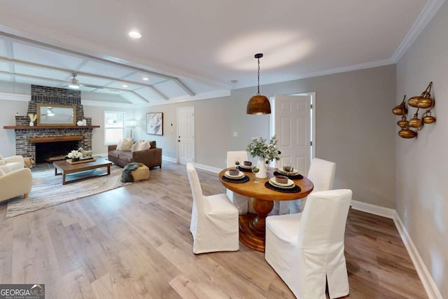 dining room with baseboards, a fireplace, a ceiling fan, and light wood finished floors