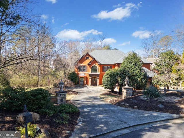 view of front of home featuring concrete driveway, a balcony, and a shingled roof