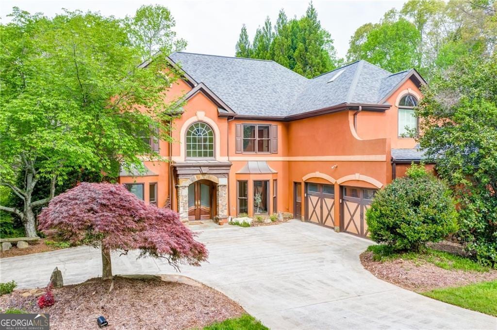 view of front of property with stucco siding, stone siding, a garage, and concrete driveway