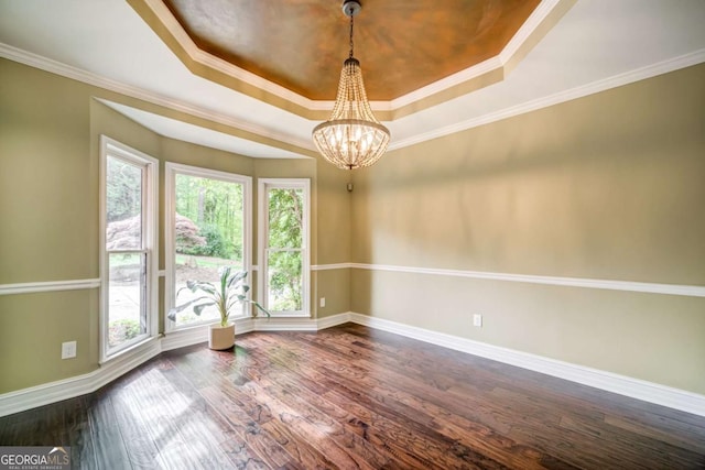 empty room featuring dark wood-style flooring, crown molding, baseboards, a raised ceiling, and an inviting chandelier