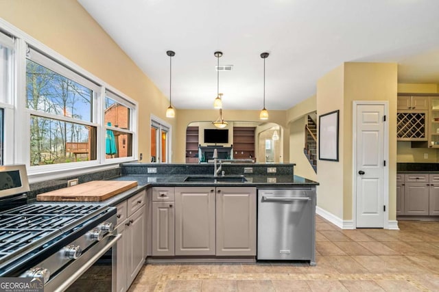 kitchen with visible vents, gray cabinetry, a sink, stainless steel appliances, and arched walkways