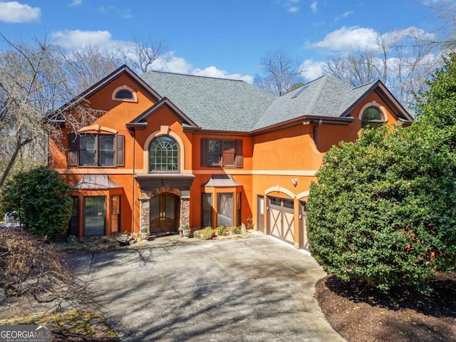 view of front of home with stone siding, stucco siding, driveway, and a garage