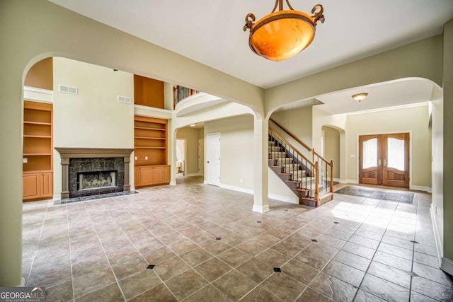 tiled entrance foyer with visible vents, arched walkways, stairway, and french doors