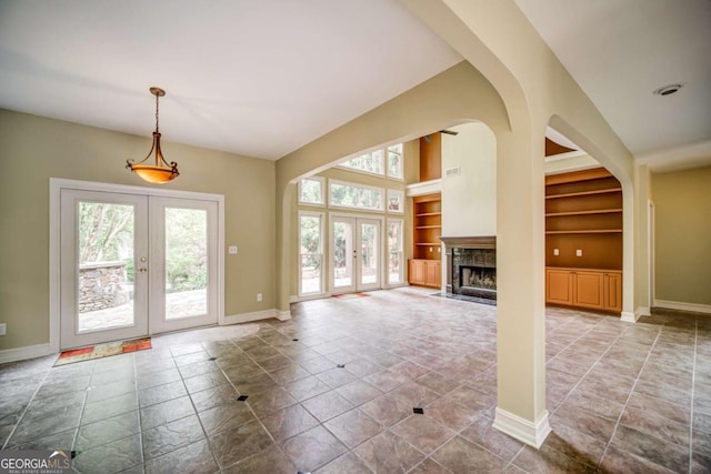 unfurnished living room with visible vents, built in shelves, french doors, a fireplace, and baseboards