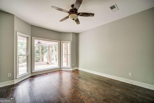 empty room with visible vents, baseboards, ceiling fan, and dark wood-style flooring