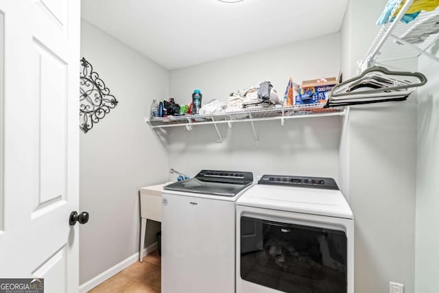 washroom with baseboards, independent washer and dryer, light tile patterned flooring, and laundry area