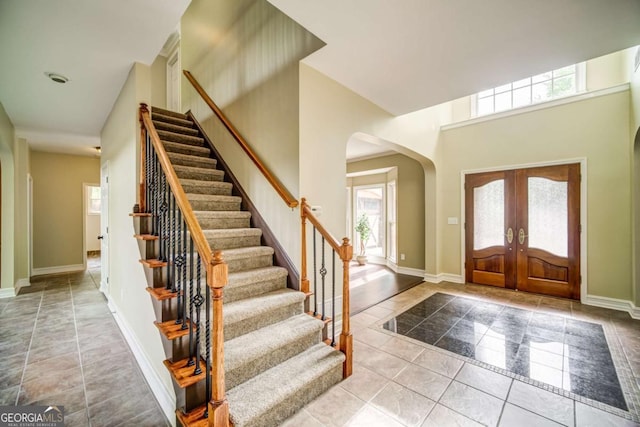 foyer featuring tile patterned floors, stairway, and arched walkways