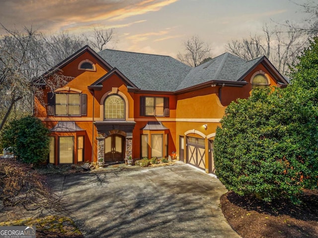 view of front of home featuring stone siding, stucco siding, driveway, and a shingled roof