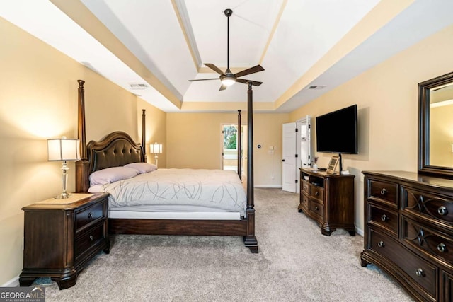 bedroom with a tray ceiling, baseboards, light colored carpet, and visible vents