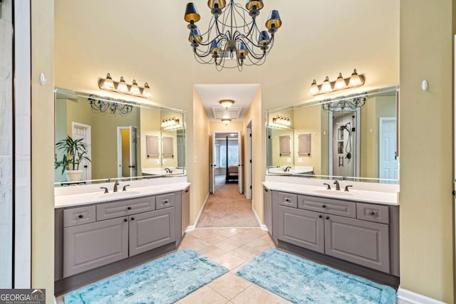 bathroom featuring tile patterned floors, a notable chandelier, two vanities, and a sink