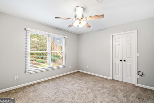 carpeted spare room featuring a ceiling fan and baseboards