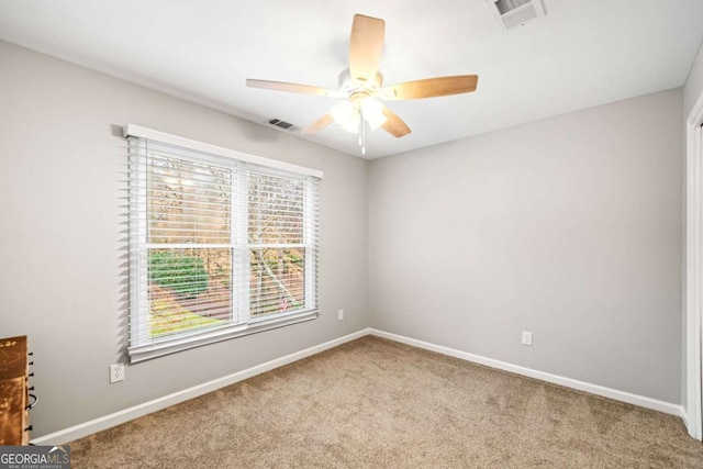 unfurnished room with visible vents, carpet floors, baseboards, and a ceiling fan