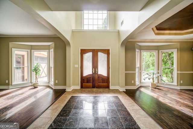 foyer entrance featuring baseboards, arched walkways, and a healthy amount of sunlight