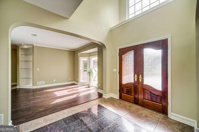 foyer featuring visible vents, baseboards, granite finish floor, french doors, and arched walkways