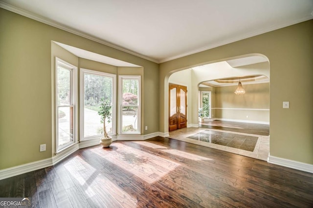 entrance foyer featuring baseboards, arched walkways, wood-type flooring, and crown molding