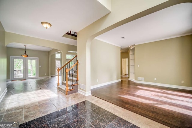 spare room featuring visible vents, granite finish floor, french doors, arched walkways, and baseboards