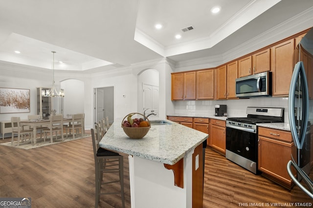 kitchen with visible vents, a tray ceiling, arched walkways, a sink, and appliances with stainless steel finishes