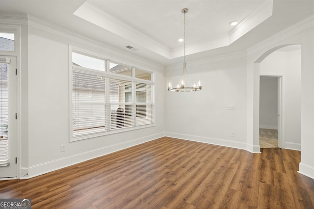 unfurnished dining area with a raised ceiling, a healthy amount of sunlight, and arched walkways