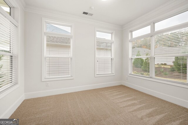 spare room with visible vents, light carpet, baseboards, and ornamental molding