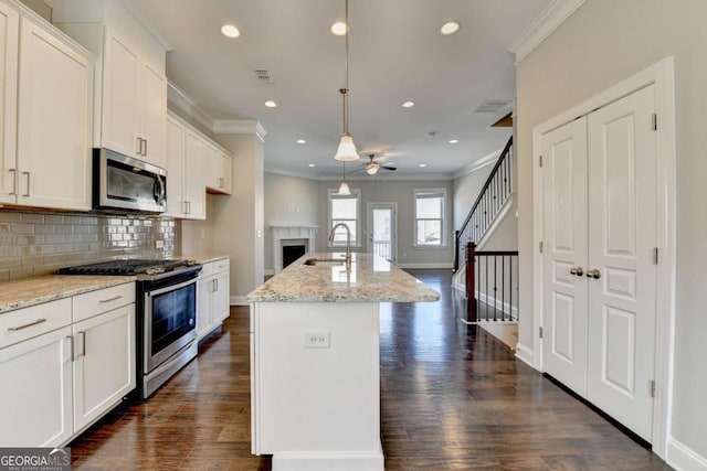 kitchen with tasteful backsplash, dark wood-type flooring, ceiling fan, appliances with stainless steel finishes, and a sink