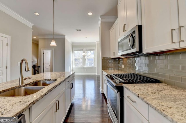 kitchen with a sink, decorative backsplash, gas range oven, white cabinetry, and stainless steel microwave