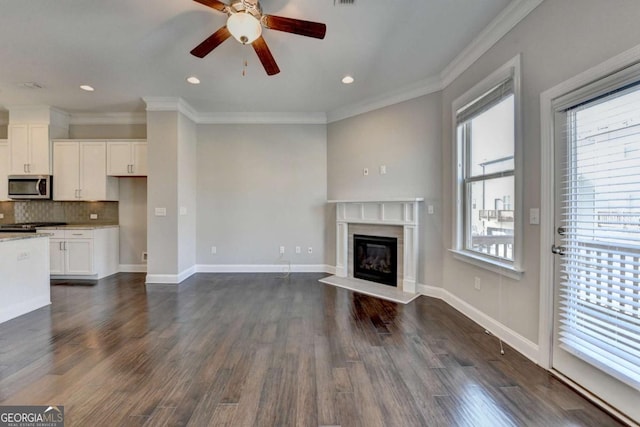 unfurnished living room featuring ornamental molding, a ceiling fan, dark wood-style floors, a fireplace, and baseboards