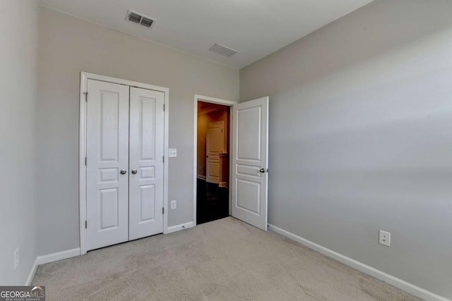 unfurnished bedroom featuring light colored carpet, baseboards, and visible vents