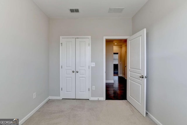 unfurnished bedroom featuring visible vents, baseboards, light colored carpet, and a closet