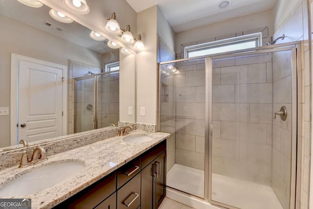 bathroom featuring double vanity, visible vents, a shower stall, and a sink