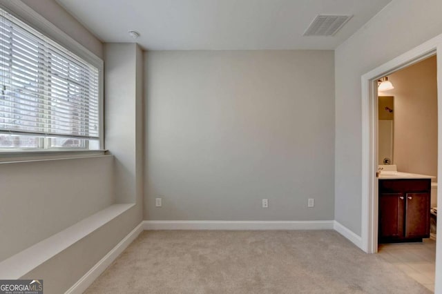 unfurnished bedroom featuring light carpet, visible vents, connected bathroom, and baseboards