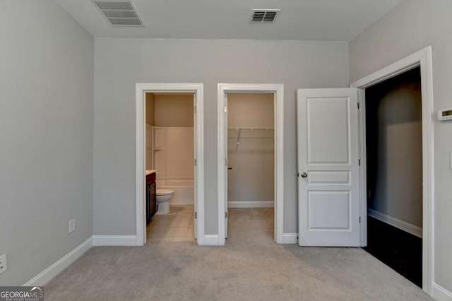 unfurnished bedroom featuring a spacious closet, visible vents, a closet, and carpet floors